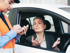 Frau bekommt einen Strafzettel von einer Politesse.