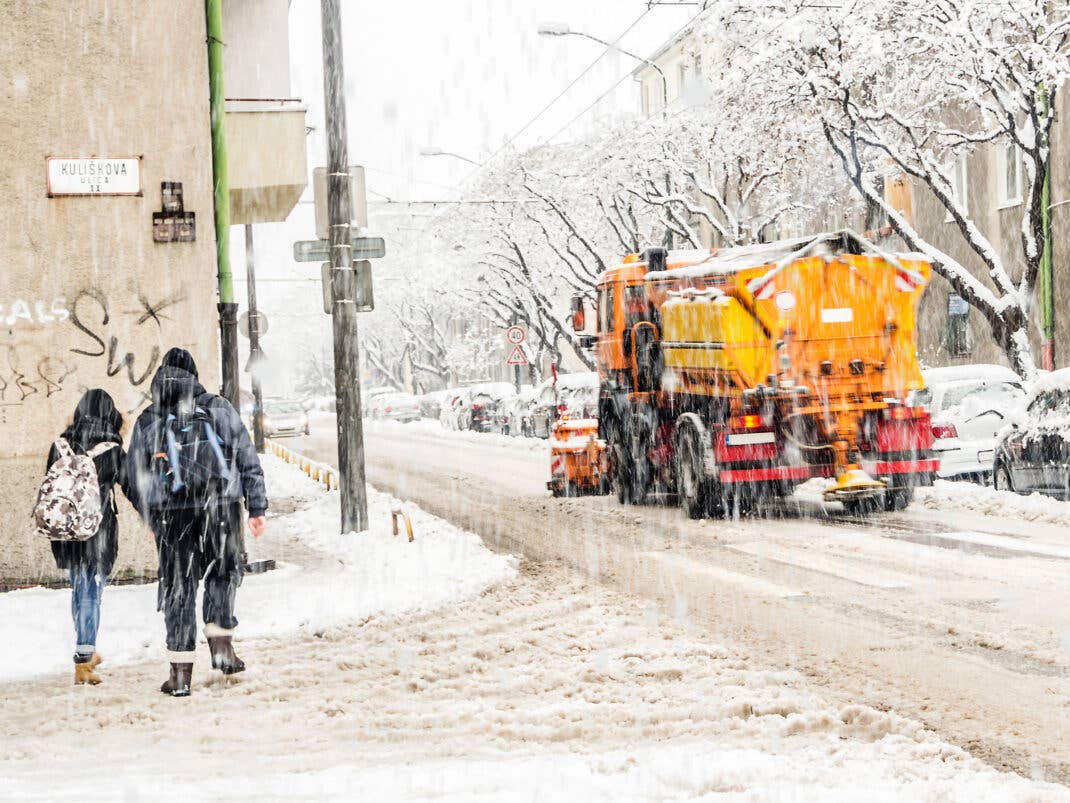Verschneite Straßen mit Schneematsch und eingeschneiten Fahrzeugen