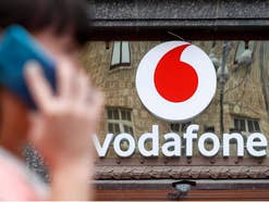 Frau telefoniert mit einem Smartphone vor einem Vodafone-Geschäft.