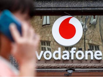 Frau telefoniert mit einem Smartphone vor einem Vodafone-Geschäft.