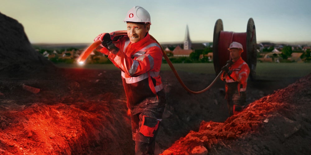 Bauarbeiter ziehen Glasfaserkabel für das Giganetz von Vodafone.