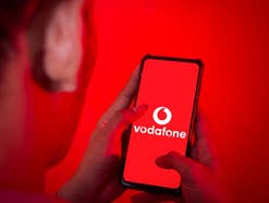 Ein Mann schaut auf sein Handy, auf dem das Vodafone-Logo zu sehen ist