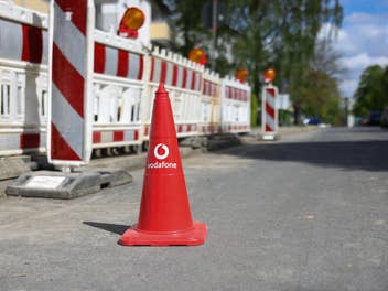 Ein Warn-Hütchen mit Vodafone-Logo vor einer Baustelle