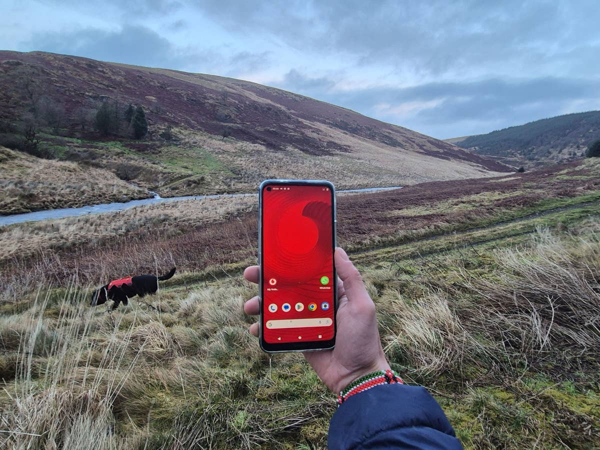 Ein Handy mit einem Vodafone-Logo vor der weiten Landschaft von Wales