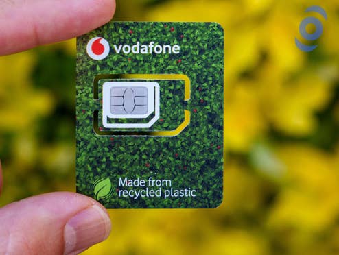 Vodafone-SIM-Karte in grünem "Recycling"-Träger mit inside digital Logo vor Natur-Hintergrund.