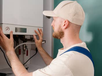 Handwerker arbeitet an einer Gasheizung (Therme)