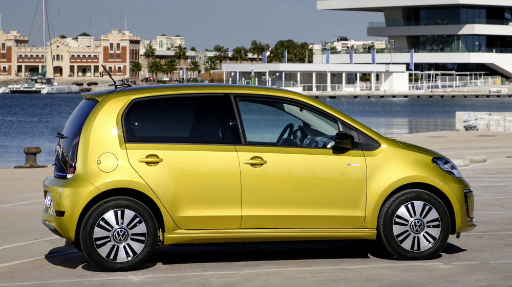Volkswagen e-Up in Gelb in der Seitenansicht in einem Hafen.