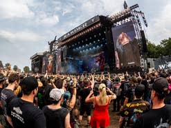 Blick auf das Wacken Open Air. Zu sehen ist eine Bühne vor dem das Publikum feiert