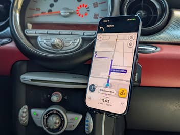 Smartphone mit aktiver Waze-Navigation in einem MINI vor dem charakteristischen runden Zentralinstrument