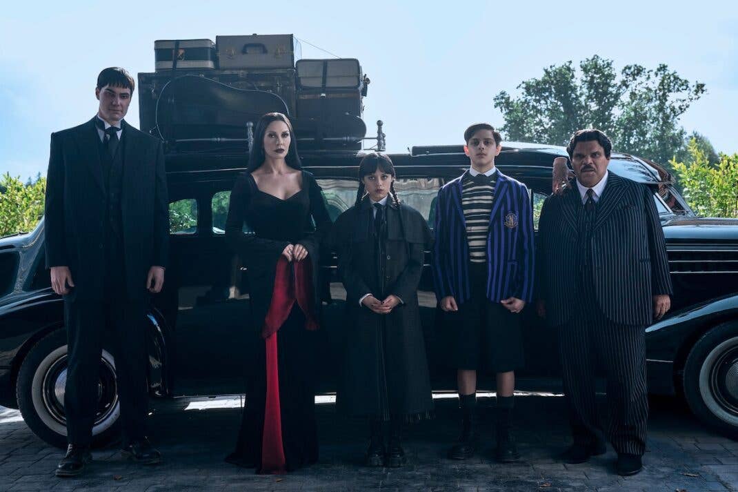 Die Addams Familie steht vor einem Oldtimer mit Gepäck.