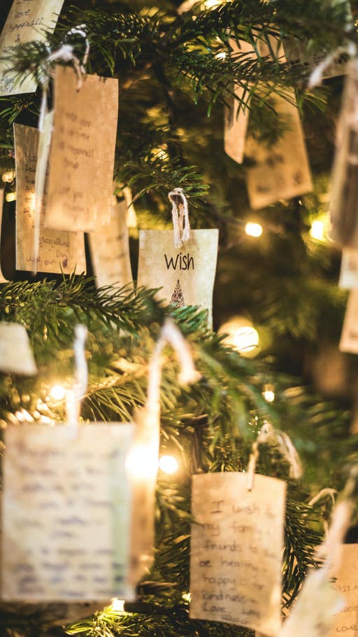 Wunschzettel auf braunem Papier, die an einem Tannenbaum hängen.