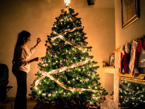 Eine Frau schmückt einen Tannenbaum.