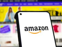 Amazon Logo auf Smartphone vor Screenshot der Amazon-Webseite