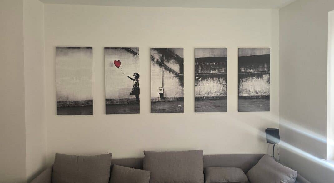 Wohnzimmer-Bild mit Couch und fünf Bildern an der Wand