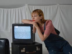 Eine Frau sitzt an einem Fernseher, der kein Bild anzeigt
