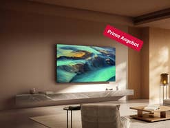 Xiaomi F Pro hängt an einer beigen Wand in einem modernen Wohnzimmer mit einem angeschalteten Bildschirm.
