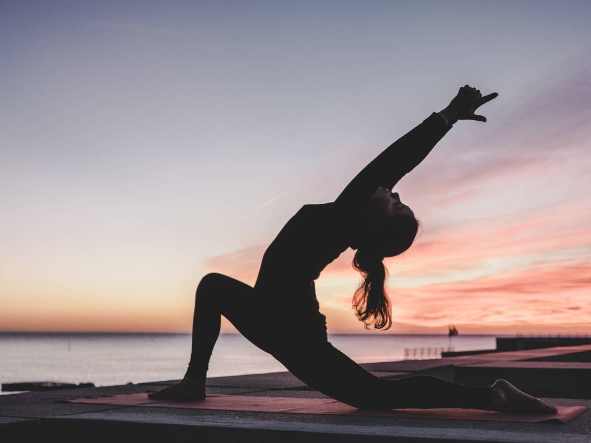 Eine Frau macht Sport und Yoga unter freiem Himmel.
