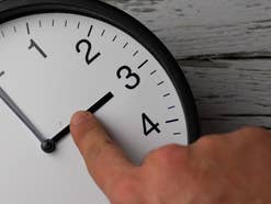 Finger zeigt auf Uhr