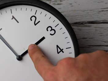 Finger zeigt auf Uhr