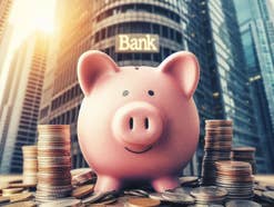 Sparschwein steht auf Münzen vor einer Bank.