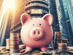 Zinsen für Tagesgeld und Festgeld massiv unter Druck Sparschwein steht auf Münzen vor einer Bank.
